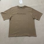 T-shirt beige Acne Studios con logo minimalista, design oversize e stile contemporaneo.