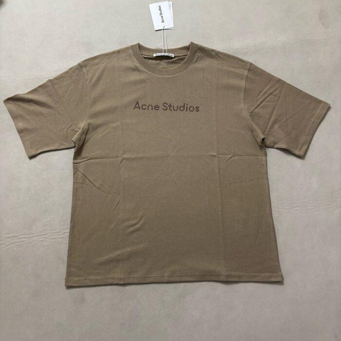 T-shirt beige Acne Studios con logo minimalista, design oversize e stile contemporaneo.