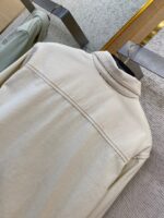 Giacca beige in tessuto rigato su appendiabiti in negozio elegante e moderno.
