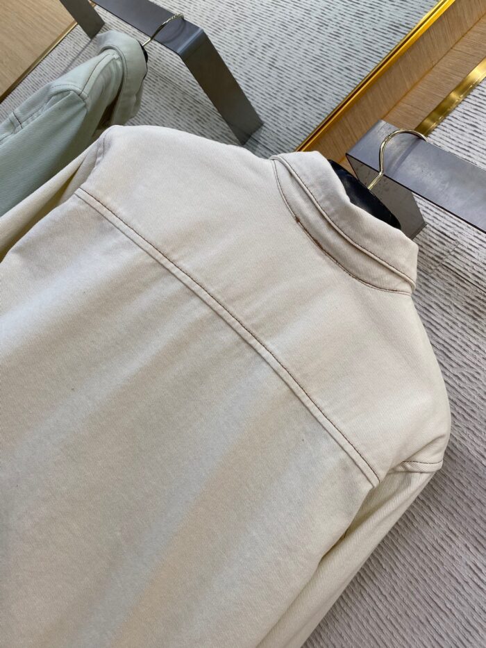 Giacca beige in tessuto rigato su appendiabiti in negozio elegante e moderno.