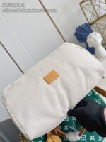 Cosmetico beige in tessuto con dettaglio in pelle, elegante e minimalista, con sfondo verde decorativo.