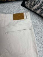 Jeans beige moderni con logo in pelle, tasca minimalista e dettagli metallici.
