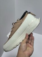 Sneaker beige trendy con suola spessa bianca, dettagli neri e design moderno.