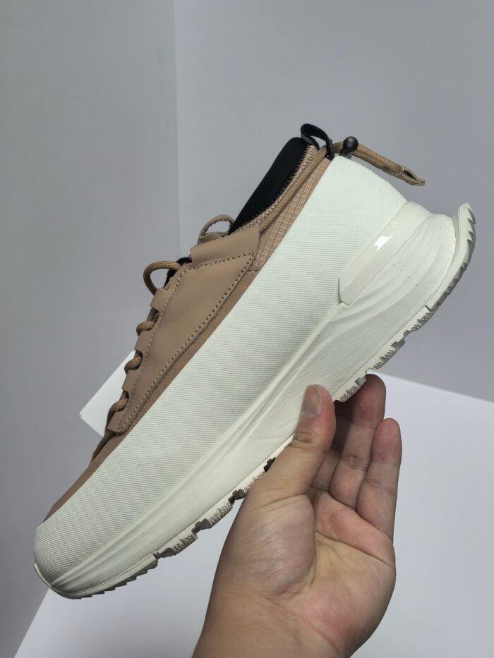 Sneaker beige trendy con suola spessa bianca, dettagli neri e design moderno.