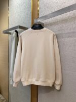 Maglione beige minimalista in cotone, stile casual ed elegante, in esposizione su hanger nello store.