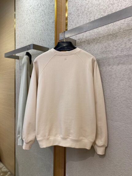Maglione beige minimalista in cotone, stile casual ed elegante, in esposizione su hanger nello store.
