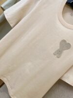 T-shirt beige basic con ricamo cuore o nodo per uno stile casual ed elegante.