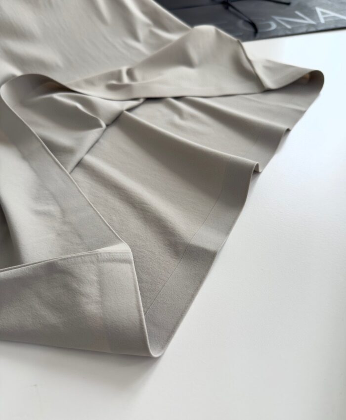 Tessuto beige elegante con morbidi drappeggi, ideale per moda e interior design raffinato.