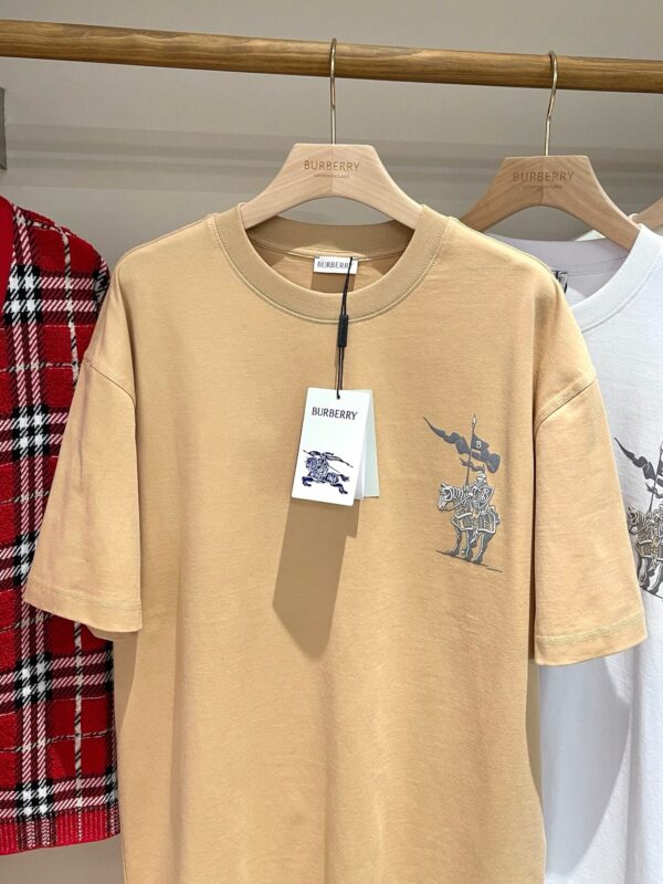 T-shirt beige con ricamo unicorno, stile casual moderno, su sfondo di abbigliamento trendy.