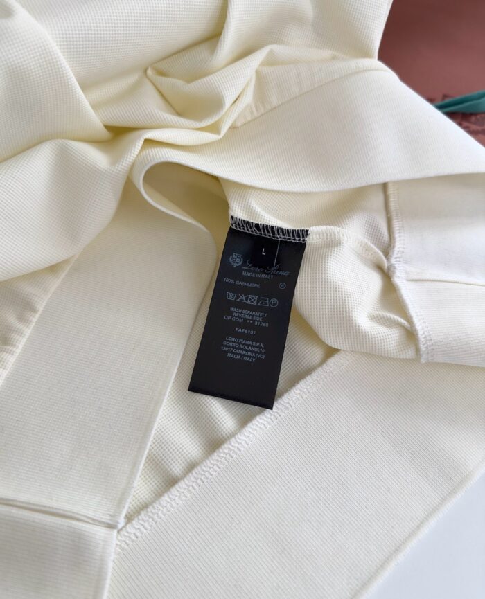 Etichetta cura su vestito crema in tessuto elegante, dettagli di manutenzione e materiali.