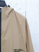 Giacca beige leggera con cappuccio e grafica naturale, perfetta per uno stile casual e pratico.