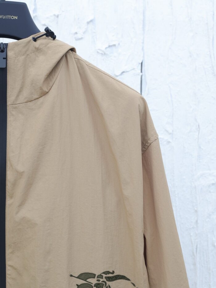 Giacca beige leggera con cappuccio e grafica naturale, perfetta per uno stile casual e pratico.