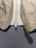 Giacca beige con zip dorata e dettagli funzionali, stile elegante e pratico.