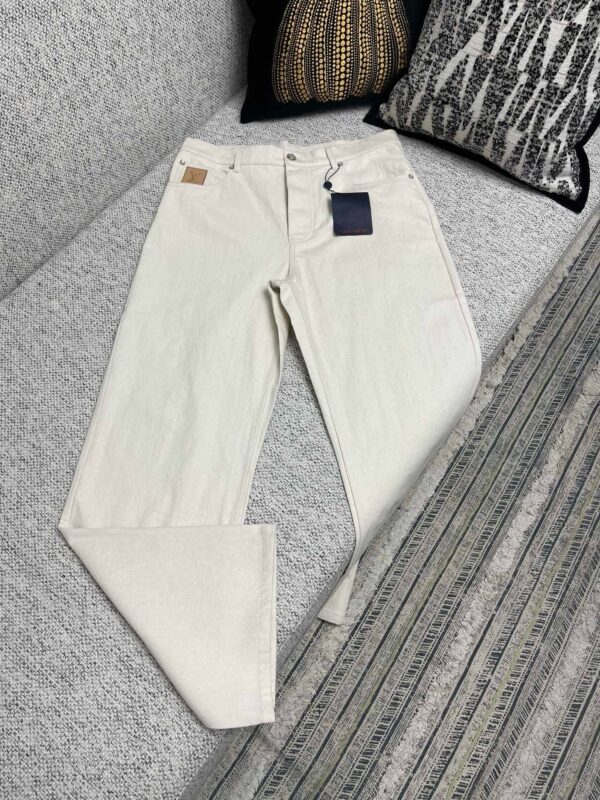 Pantaloni beige casual su divano con cuscini decorativi e stile moderno.