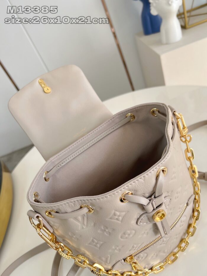 Borsa a secchiello beige con catena doro e design di lusso elegante e versatile.