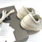 Sneakers beige minimaliste in packaging elegante, perfette per stile casual e sofisticato.