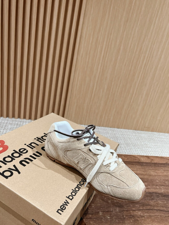 Sneaker New Balance beige made in USA su pavimento in legno, con scatola e dettagli premium.