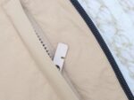 Chiusura a zip su giacca beige casual, dettaglio resistente e moda semplice.
