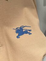 Maglietta polo beige con logo ricamato di cavallo in blu, stile classico e versatile.