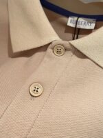 Maglietta polo beige Burberry, tessuto testurizzato, dettaglio navy, bottoni eleganti, stile raffinato.