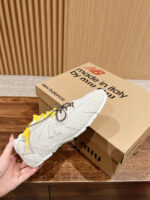 Sneaker beige con logo New Balance, lacci gialli vivaci, stile moderno e qualità italiana.