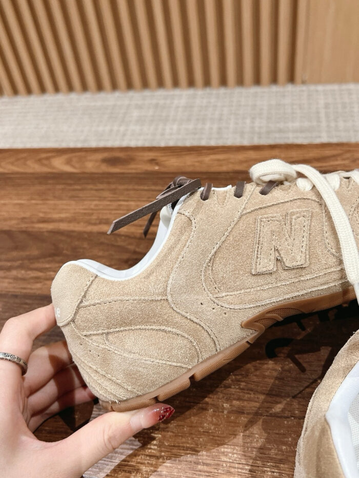 Sneaker beige in suede e pelle con logo N, sfondo in legno, dettaglio elegante e casual.