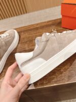 Sneaker beige in pelle scamosciata con suola bianca, stile moderno e raffinato.