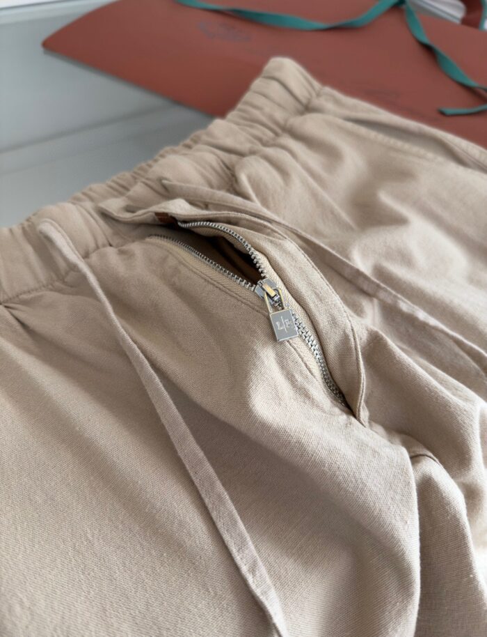 Pantaloni sportivi beige con cintura elastica, zip e stile casual per il relax.