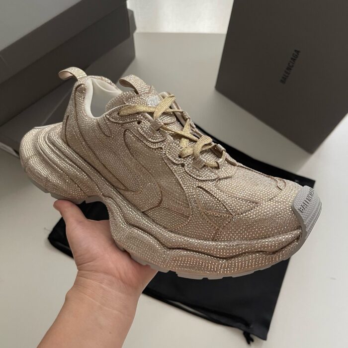 Sneaker beige moderna con suola chunky, dettagli texturizzati e finitura metallizzata elegante.