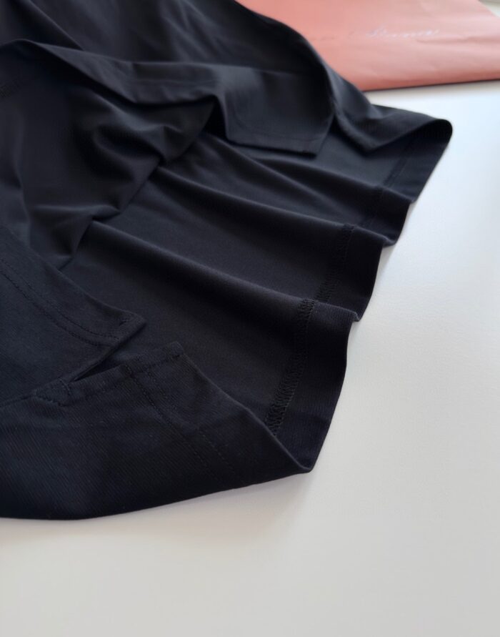 Tessuti eleganti nero lucido e rosa chiaro con drappeggio raffinato, perfetti per moda e design.