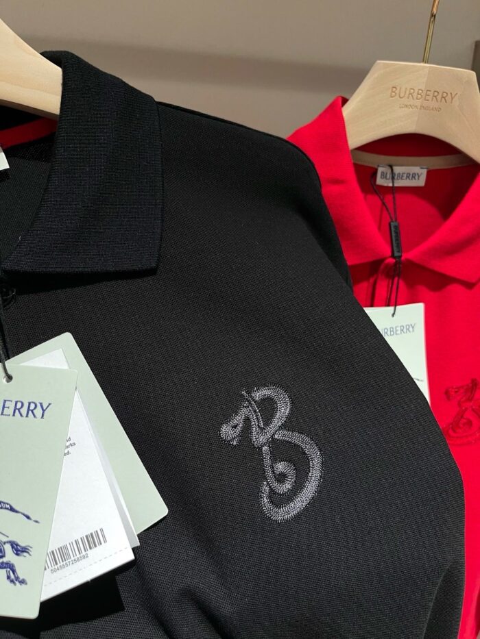 Magliette polo nere ed rosse eleganti con logo discreto e tag verde su appendiabiti.