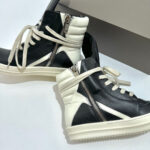 Sneakers high-top in pelle bicolore con zip diagonale, suola antiscivolo e stile urbano moderno.