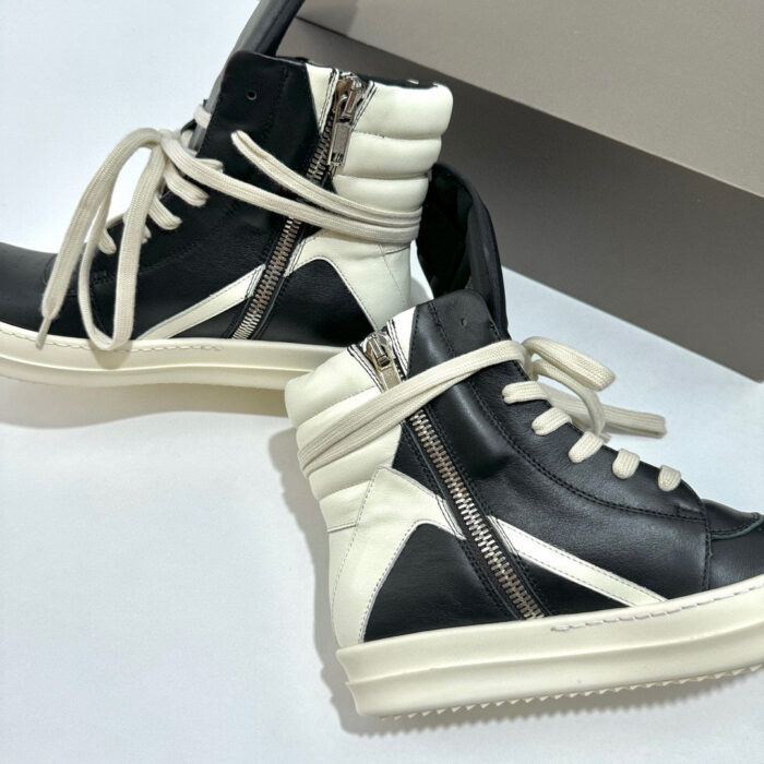 Sneakers high-top in pelle bicolore con zip diagonale, suola antiscivolo e stile urbano moderno.