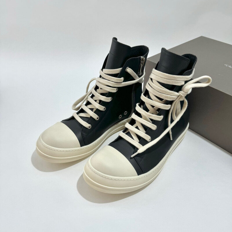 Sneakers alte nere e bianche moderne con lacci crema e dettagli eleganti.