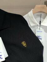 Polo di lusso Burberry nero e bianco con logo dorato e dettagli eleganti.