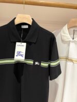 Polo uomo con strisce colorate e logo elegante su sfondo minimalista in legno naturale.