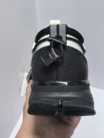 Scarpa atletica nera con cinturino bianco, suola robusta e design moderno per sport e casual.