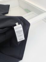 Dettaglio di abbigliamento nero con etichetta semplice, tessuto moderno e riflessi eleganti.