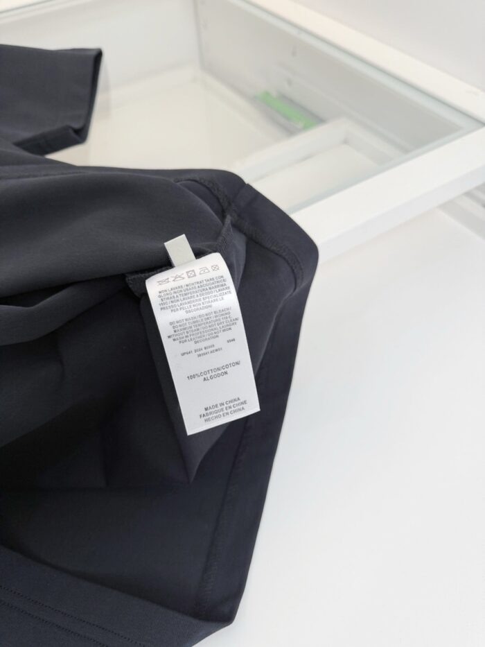 Dettaglio di abbigliamento nero con etichetta semplice, tessuto moderno e riflessi eleganti.