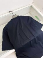 Maglietta nera minimalista su appendiabiti in esposizione, perfetta per look casual e moderni.