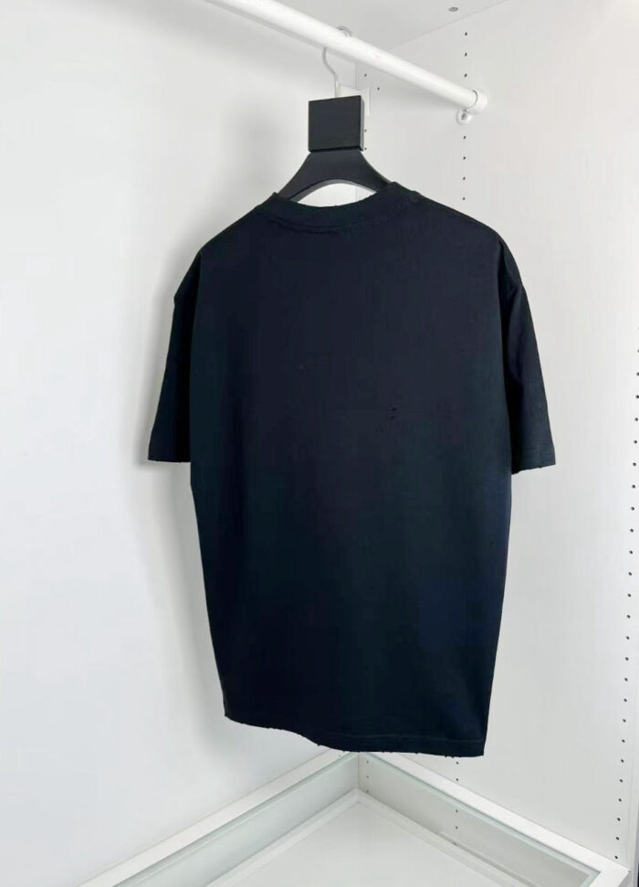 Maglietta nera semplice con scollo a giro, hanger e sfondo bianco.