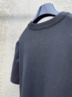 Maglietta nera casual a girocollo su gancio blu, tessuto morbido e stile semplice e moderno.