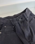 Pantaloni in denim grigio vintage con cintura, bottoni metallici e cuciture robuste.