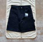 Shorts in denim nero con dettagli gold, tasche multiple e logo embossato, stile casual e trendy.