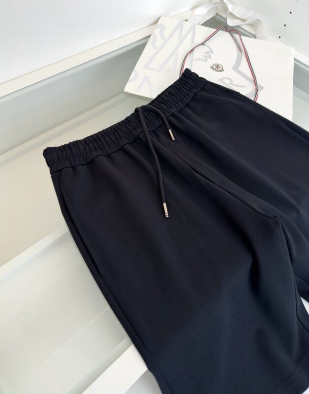 Pantaloni jogger neri in tessuto elastico con elastico regolabile e dettagli metallici.