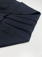 Tessuto nero elegante con finiture meticulous, ideale per abbigliamento moderno e sofisticato.