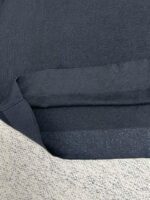 Dettaglio di maglia nera in cotone con bordo a costine, elegante e versatile.