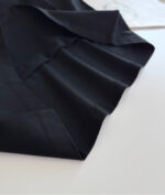 Tessuto nero lucido con drappeggio elegante, ideale per abbigliamento di alta qualità.