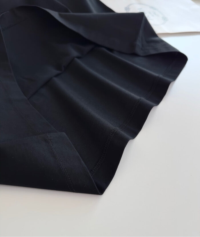 Tessuto nero lucido con drappeggio elegante, ideale per abbigliamento di alta qualità.