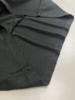 Tessuto nero di alta qualità con cuciture precise e finiture impeccabili, ideale per abbigliamento elegante.